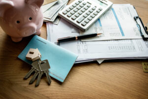 Piggy bank, house keys, calculator and bills in preparation for refinancing